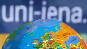 Blick auf einen Spielball, der die Erde darstellt und der Uni Jena Slogan im Hintergrund.