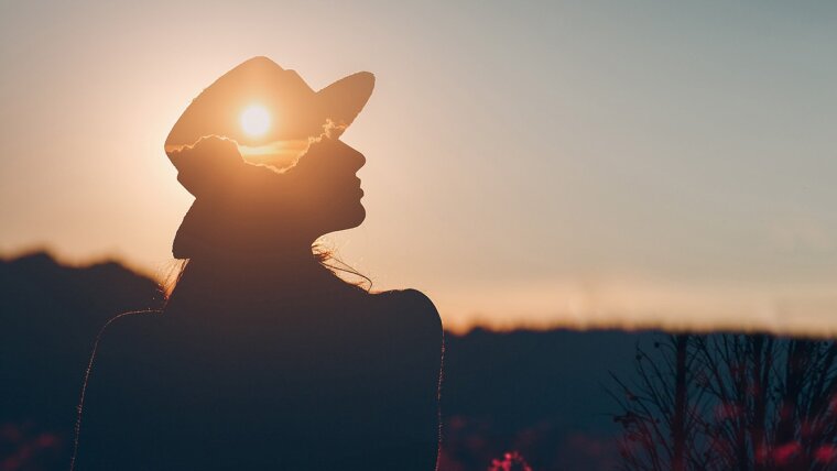Junge Frau im Sonnenuntergang mit abgebildeter Gedankenlandschaft