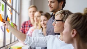 A team develops ideas and sticks notes on a window